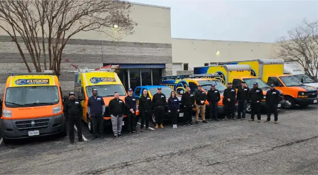 The entire Fusion Home Services technician team standing together in front of their work vehicles