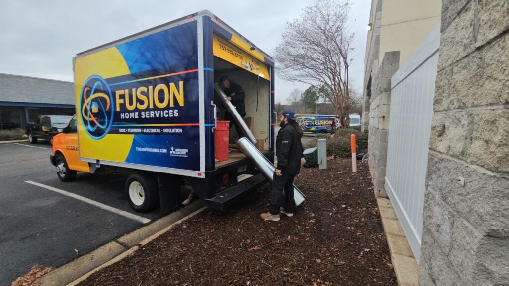 Technicians working on HVAC equipment in Fusion Home Services truck.