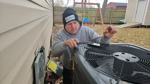 HVAC technician fixing outdoor air conditioning unit in backyard.